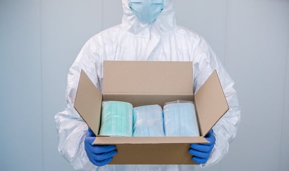 Operator in Cleanroom mask and coverall opens a box and show the packing of new surgical masks