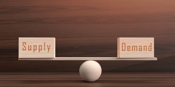 Image depicting a wooden cube with a square and circular shape on a seesaw. The text includes supply and demand