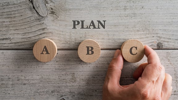 Businessman hand flipping wooden cube blocks with PLAN A change to PLAN B text