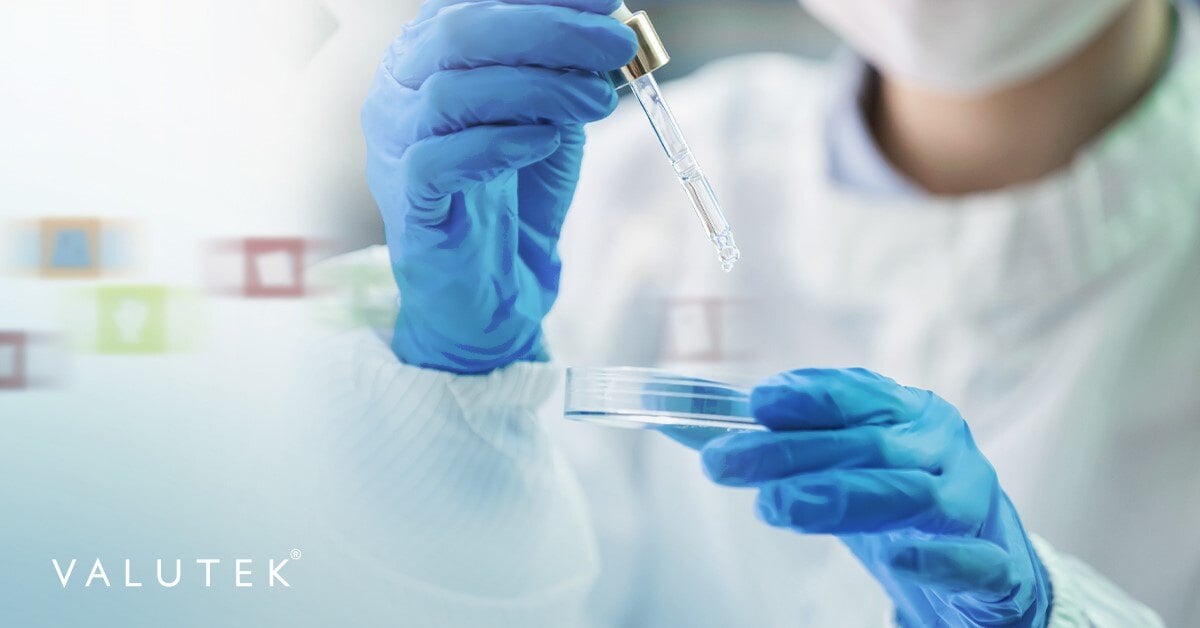 Cleanroom technician holding a petri dish while wearing cleanroom gloves and coverall.